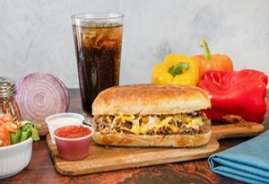 Genos Giant Slice sandwich on wooden board with side dishes and drink, Arizona pizzeria offering hearty meal.