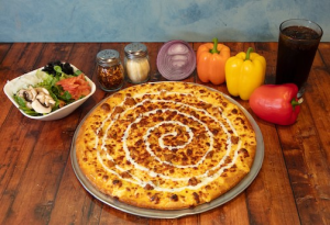 image001 Genos Giant Slice pizza with spiral cheese drizzle, served with sides and drinks on wooden table