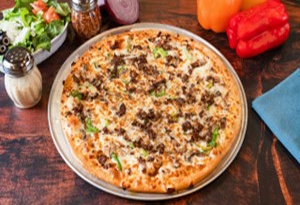 Genos Giant Slice pizza on metal tray with toppings, surrounded by peppers, onions, and condiments on wooden surface