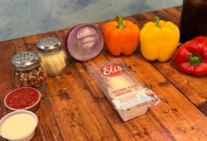 Genos Giant Slice pizza packaging on wooden table with fresh vegetables and condiments nearby