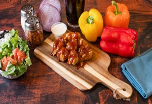 Genos Giant Slice pizza served on wooden board with fresh vegetables, salad, and condiments on rustic table